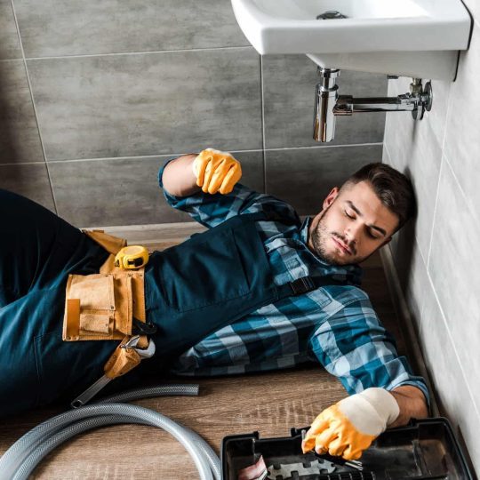 bearded-handyman-lying-on-floor-near-toolbox-in-bathroom-qbc432qw2q1r955i8bw9gfgiur3bccbgh4288ew5y0