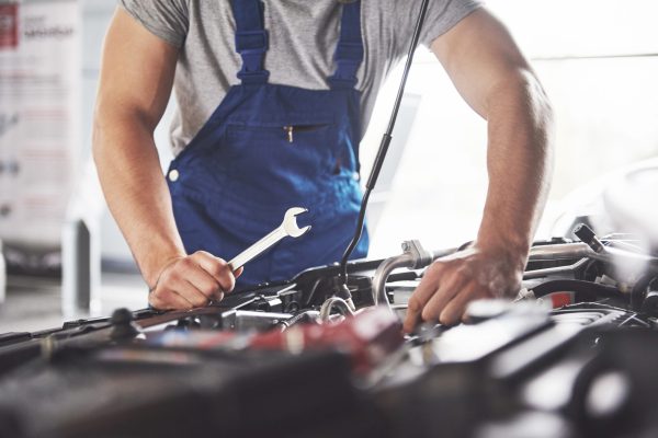 Picture showing muscular car service worker repairing vehicle.