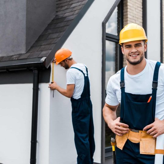 selective-focus-of-happy-handyman-in-uniform-near-coworker